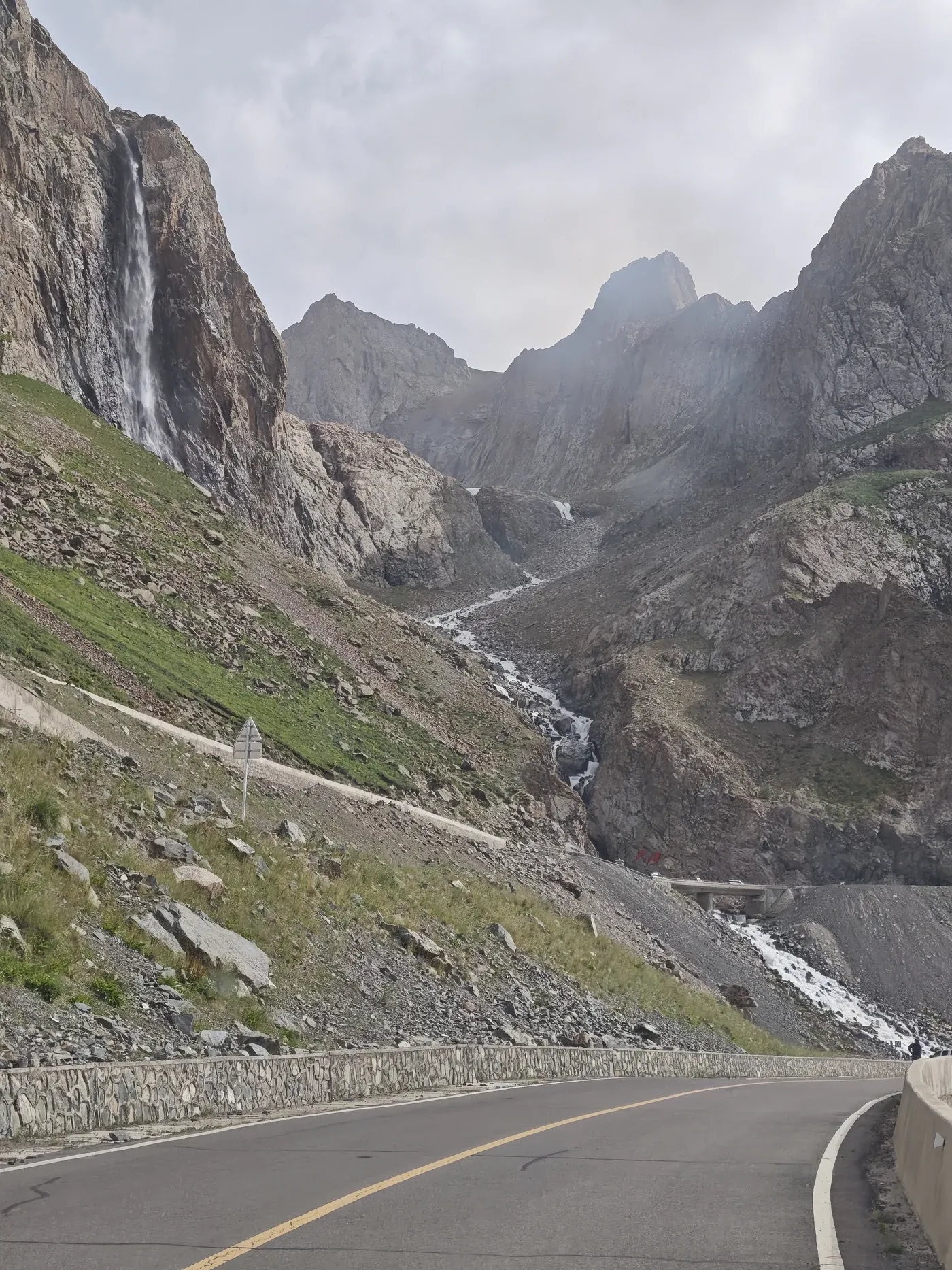 Entering the Tianshan, the road begins to follow rock, water and whatever space the mountains allow. Duku Highway, July 2026.